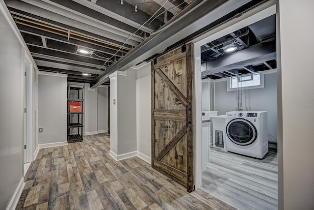 basement with washer / clothes dryer, wood finished floors, a barn door, and baseboards