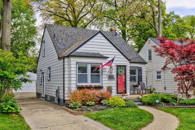 bungalow-style home with an outdoor structure, a detached garage, and a shingled roof