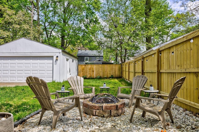 fenced backyard featuring an outdoor fire pit, an outbuilding, and a detached garage