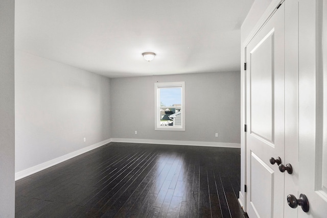 unfurnished room with dark wood finished floors and baseboards