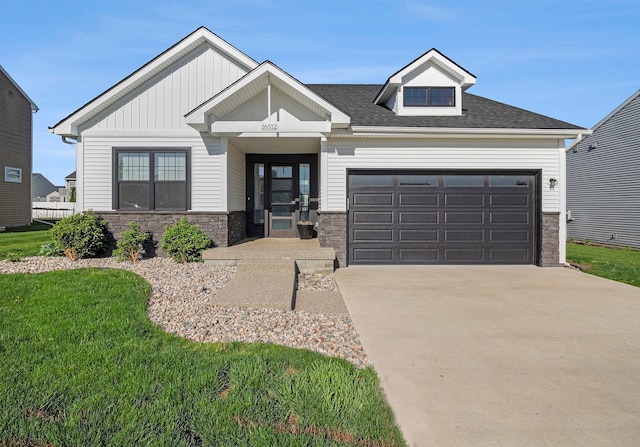 view of front facade with stone siding, an attached garage, driveway, and a front lawn
