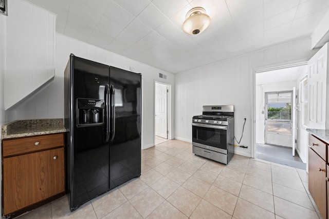 842 E 10 Mile Rd, Ferndale, MI 48220 - kitchen with black fridge with ice dispenser, stainless steel range with gas cooktop, light tile patterned floors, and light stone countertops