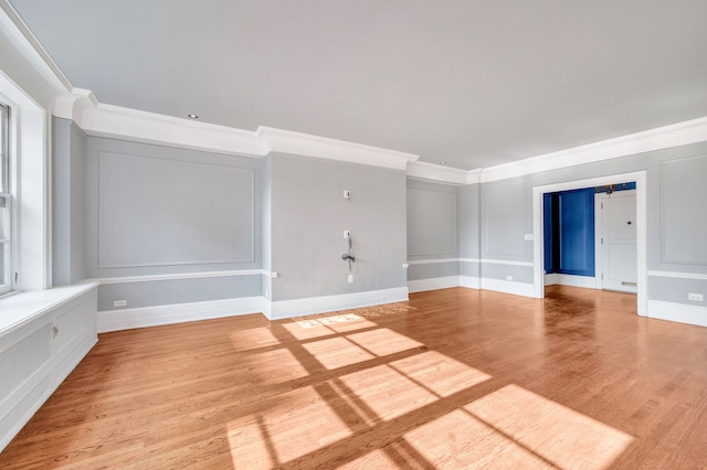 spare room featuring crown molding, light wood-style floors, and baseboards