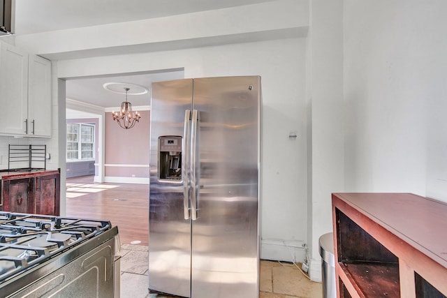 kitchen with stainless steel appliances, a chandelier, white cabinets, baseboards, and crown molding