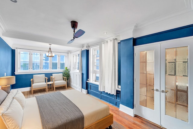 bedroom with ornamental molding, baseboards, light wood-style floors, french doors, and a ceiling fan