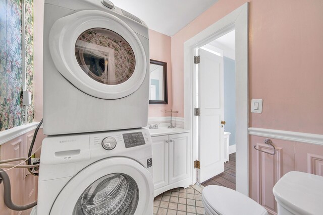 laundry room featuring estacked washer and dryer and light tile patterned floors