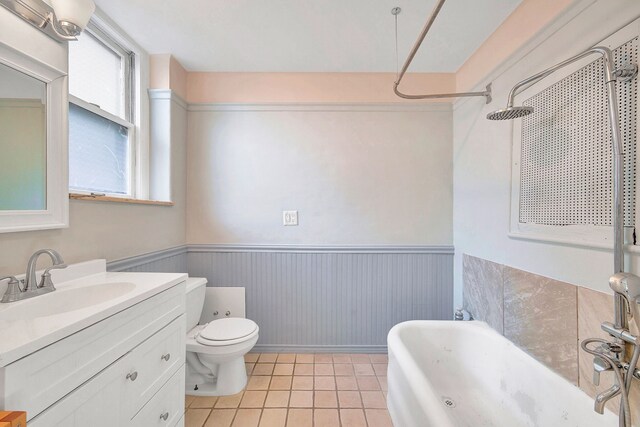bathroom featuring wainscoting, a shower, tile patterned floors, toilet, and vanity