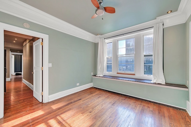 unfurnished room featuring crown molding, ceiling fan, hardwood / wood-style floors, a smoke detector, and baseboards