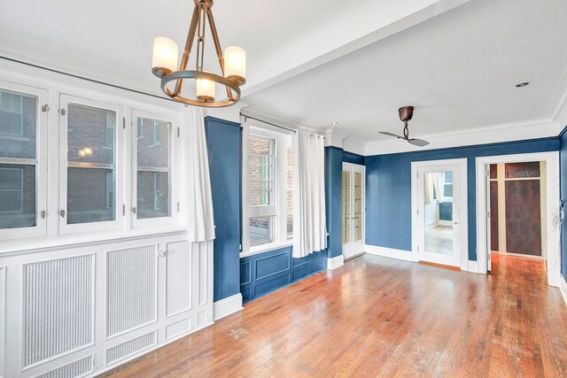 unfurnished room with a chandelier, french doors, wood finished floors, baseboards, and crown molding