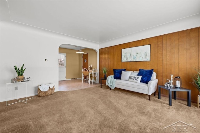 301 W Fourth St, Gladwin, MI 48624 - carpeted living room featuring arched walkways, wood walls, and baseboards