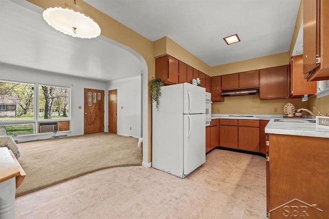 301 W Fourth St, Gladwin, MI 48624 - kitchen with white appliances, under cabinet range hood, light countertops, brown cabinetry, and a sink