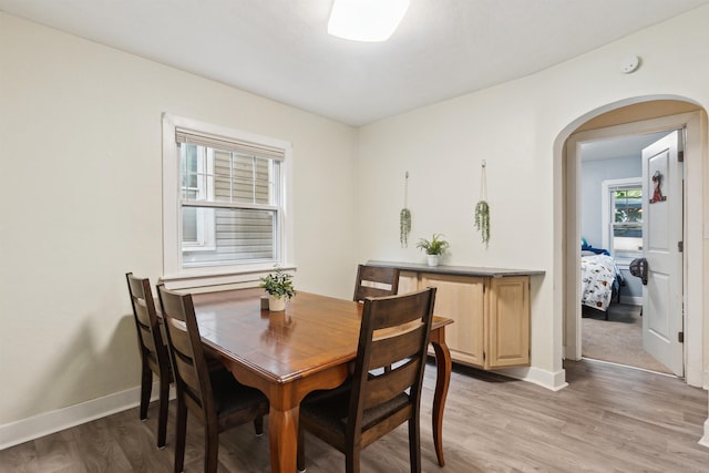 1430 New York Ave, Lansing, MI 48906 - dining space featuring arched walkways, baseboards, and light wood-style flooring