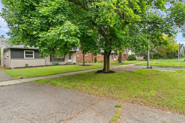 9319 Merriman Rd, Livonia, MI 48150 - obstructed view of property with brick siding, a front yard, and a chimney