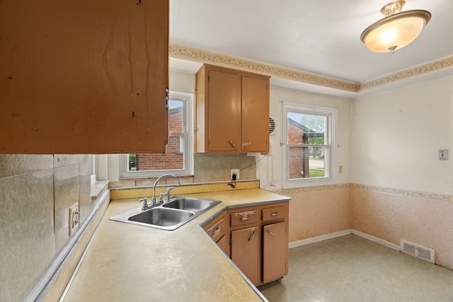 9319 Merriman Rd, Livonia, MI 48150 - kitchen with a sink, light countertops, light floors, a wainscoted wall, and brown cabinetry
