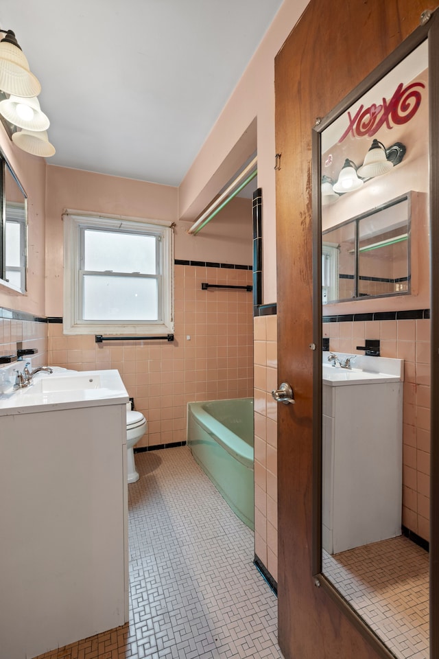 9319 Merriman Rd, Livonia, MI 48150 - bathroom featuring tile walls, a bath, vanity, toilet, and a wainscoted wall