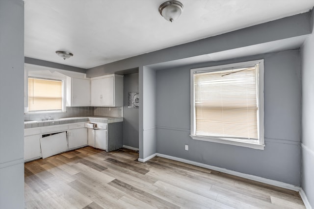9035 Braile St, Detroit, MI 48228 - kitchen with tile counters, white cabinetry, tasteful backsplash, light wood-style floors, and baseboards