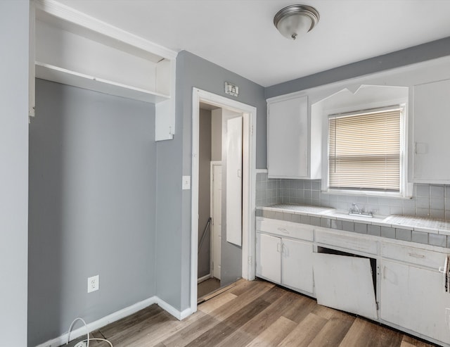 9035 Braile St, Detroit, MI 48228 - kitchen featuring tile counters, white cabinets, decorative backsplash, light wood-style floors, and a sink