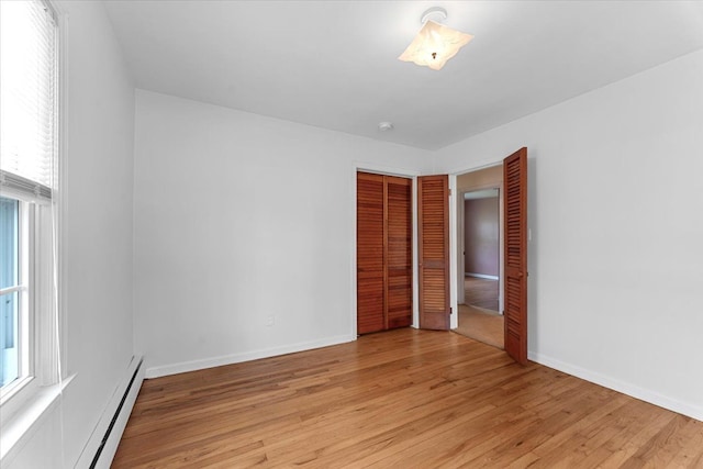 30617 Young Dr, Gibraltar, MI 48173 - unfurnished bedroom featuring a baseboard heating unit, light wood-type flooring, a closet, and multiple windows
