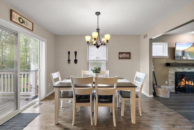 457 Cove View Dr, Waterford, MI 48327 - dining space featuring a chandelier, wood finished floors, a lit fireplace, and baseboards