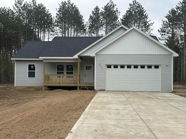 5203 NE Myers Rd, Kalkaska, MI 49646 - view of front of house with concrete driveway, covered porch, an attached garage, and a shingled roof