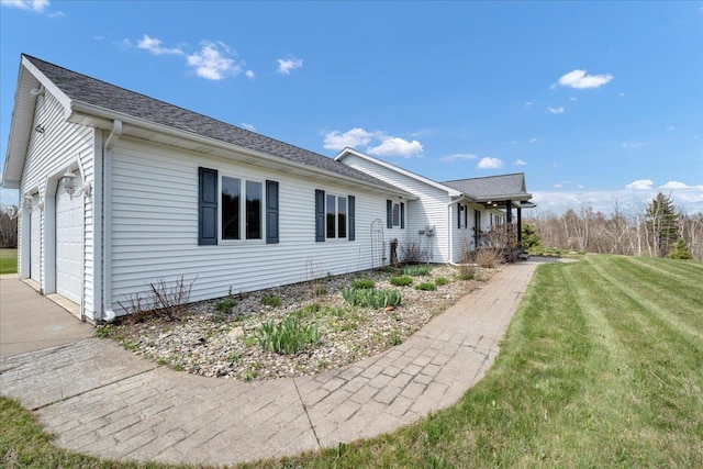 view of home's exterior with a yard, a garage, and a shingled roof