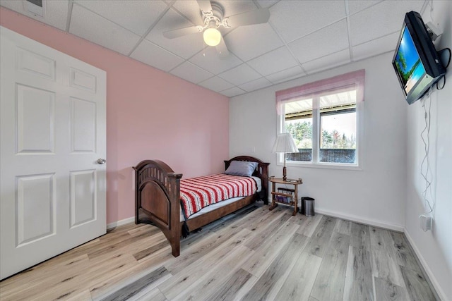 bedroom with a paneled ceiling, light wood finished floors, ceiling fan, and baseboards