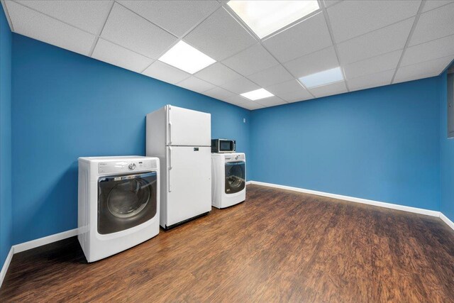 washroom with baseboards, wood finished floors, and washer and clothes dryer