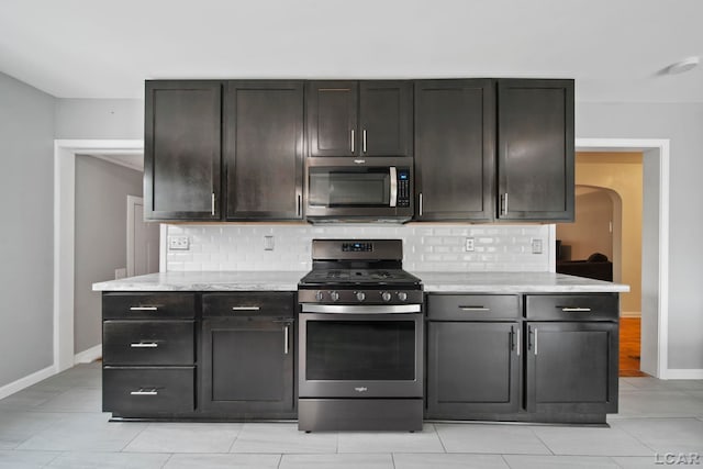1107 Sunset Dr, Tecumseh, MI 49286 - kitchen featuring appliances with stainless steel finishes, baseboards, backsplash, and arched walkways