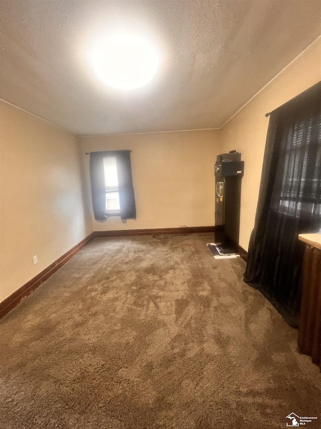 carpeted empty room with a textured ceiling and baseboards