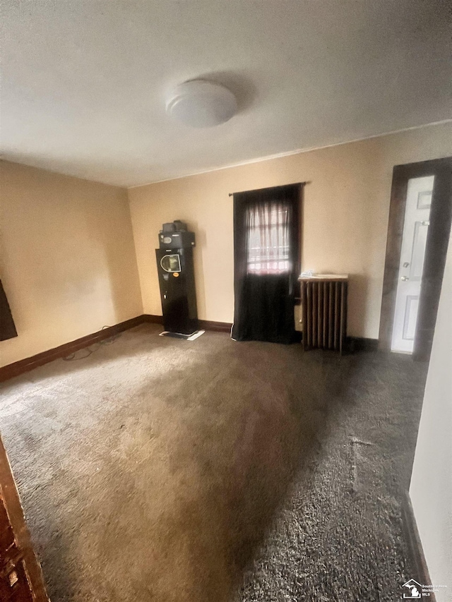 unfurnished living room featuring radiator, carpet flooring, baseboards, and water heater