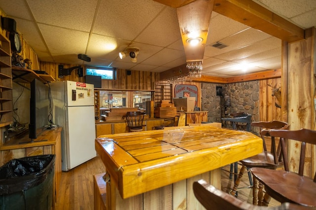 34699 Fuerstenau Rd, Richmond, MI 48062 - dining space with a wood stove, a drop ceiling, wood finished floors, and wood walls