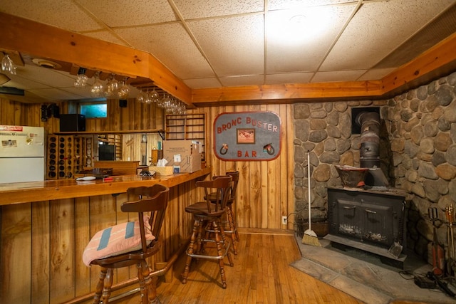 34699 Fuerstenau Rd, Richmond, MI 48062 - indoor dry bar featuring a drop ceiling, freestanding refrigerator, hardwood / wood-style flooring, wood walls, and a wood stove