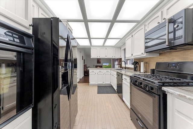 28605 Southpointe Rd, Grosse Ile, MI 48138 - kitchen featuring black appliances, white cabinetry, a sink, tasteful backsplash, and light wood finished floors