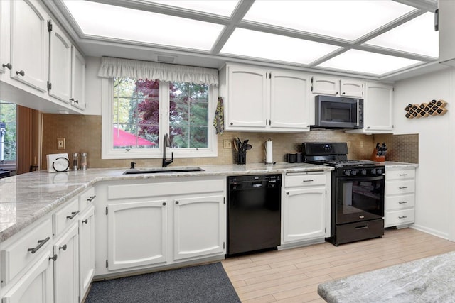28605 Southpointe Rd, Grosse Ile, MI 48138 - kitchen with black appliances, a sink, tasteful backsplash, white cabinets, and light wood finished floors