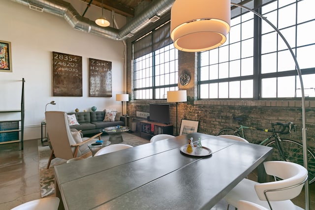 3434 Russell St Unit 28-205, Detroit, MI 48207 - dining room featuring a high ceiling, brick wall, and concrete flooring