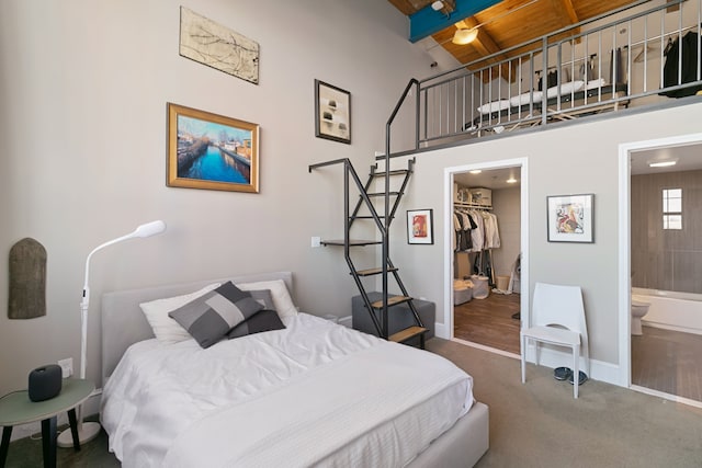 3434 Russell St Unit 28-205, Detroit, MI 48207 - bedroom with carpet floors, a walk in closet, beamed ceiling, ensuite bath, and baseboards