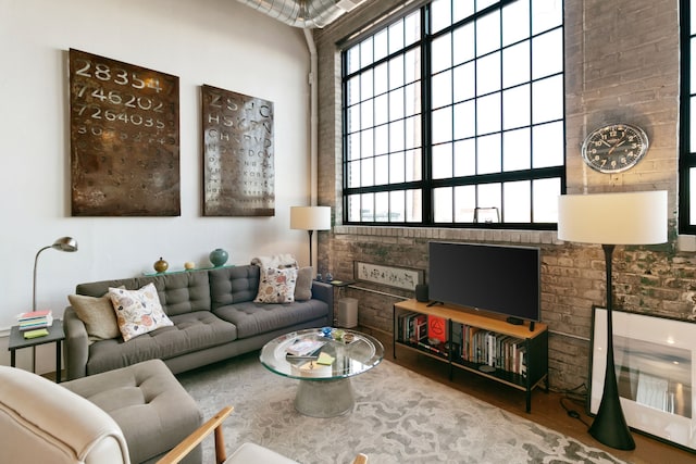 3434 Russell St Unit 28-205, Detroit, MI 48207 - living room with healthy amount of natural light, brick wall, and wood finished floors