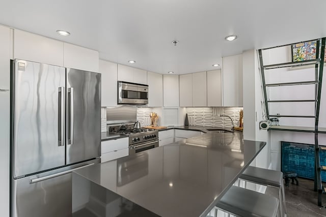 3434 Russell St Unit 28-205, Detroit, MI 48207 - kitchen featuring premium appliances, dark countertops, a sink, tasteful backsplash, and white cabinets