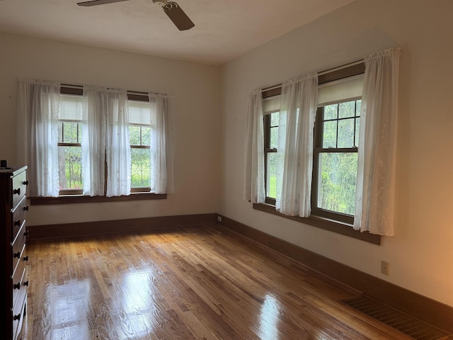 1627 S M-52 Hwy, Owosso, MI 48867 - empty room with healthy amount of natural light, a ceiling fan, wood finished floors, and baseboards