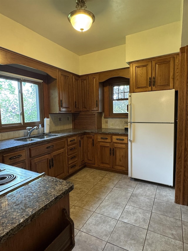 1627 S M-52 Hwy, Owosso, MI 48867 - kitchen with freestanding refrigerator, a sink, decorative backsplash, light tile patterned flooring, and brown cabinetry