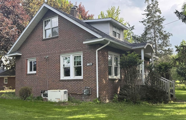 1627 S M-52 Hwy, Owosso, MI 48867 - view of property exterior with brick siding, a chimney, a yard, and central AC