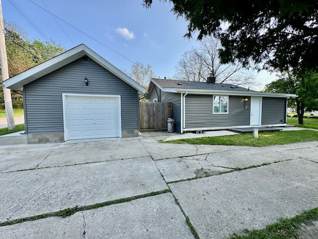 4915 Clarkston Rd, Clarkston, MI 48348 - view of front of property featuring concrete driveway, a detached garage, an outdoor structure, fence, and a chimney