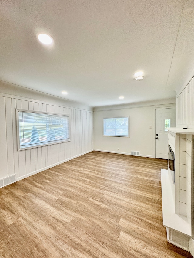 4915 Clarkston Rd, Clarkston, MI 48348 - unfurnished living room with light wood finished floors, a fireplace with raised hearth, healthy amount of natural light, a textured ceiling, and baseboards