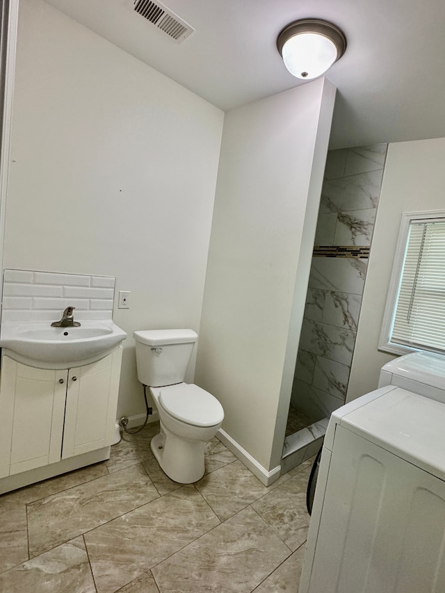 4915 Clarkston Rd, Clarkston, MI 48348 - bathroom with marble look tiles, washer and dryer, toilet, a tile shower, and baseboards
