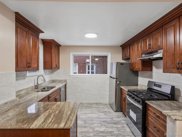 6010 Hartwell St, Dearborn, MI 48126 - kitchen with stainless steel appliances, a sink, under cabinet range hood, light stone counters, and tile walls