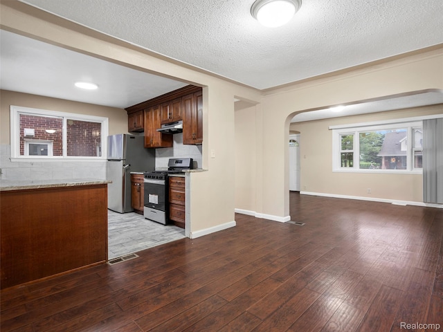 6010 Hartwell St, Dearborn, MI 48126 - kitchen featuring stainless steel appliances, under cabinet range hood, arched walkways, light wood finished floors, and backsplash
