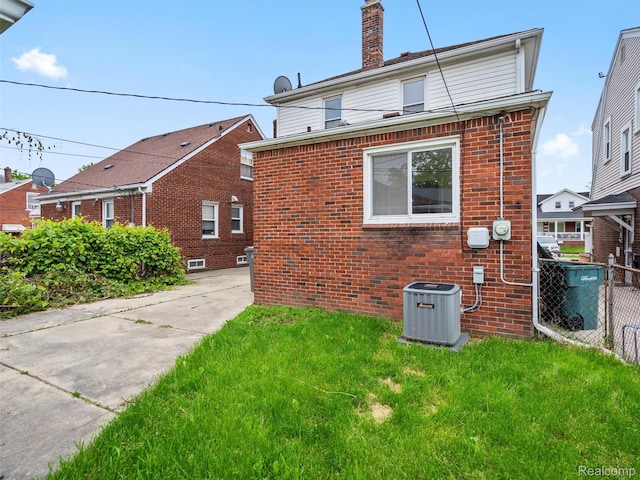 6010 Hartwell St, Dearborn, MI 48126 - rear view of house featuring central AC unit, brick siding, and a chimney
