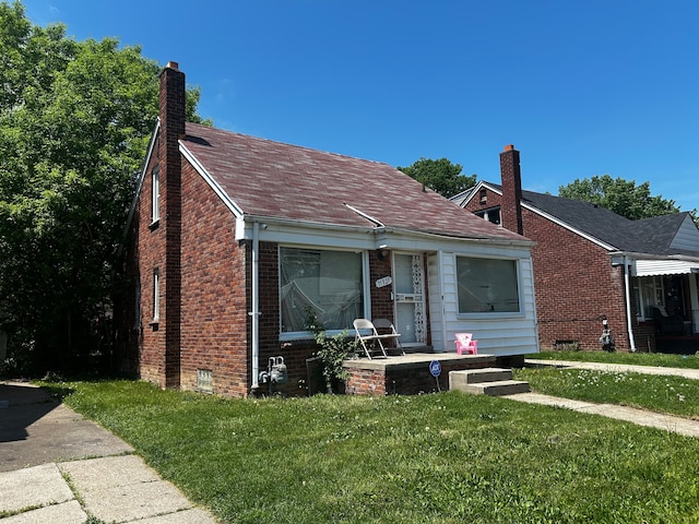 11329 Minock St, Detroit, MI 48228 - bungalow-style house featuring a front yard, brick siding, a chimney, and a porch