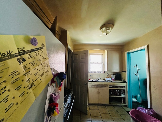 11329 Minock St, Detroit, MI 48228 - kitchen featuring tile countertops, stove, tile patterned flooring, and tasteful backsplash
