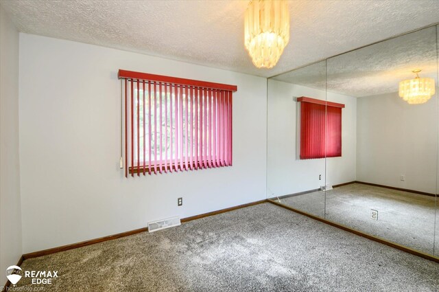 500 Granger Rd, Ortonville, MI 48462 - carpeted empty room featuring a chandelier, a textured ceiling, and baseboards